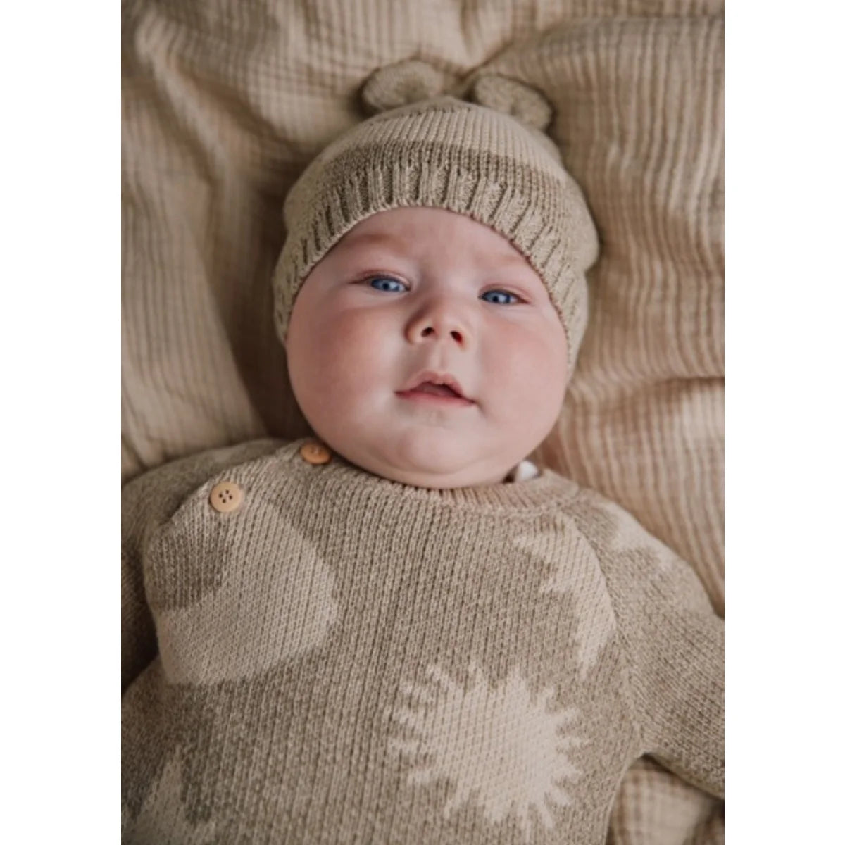 Weiches beige gestricktes Baby-Outfit mit Sonnenstrahlsmuster und passender Mütze mit Pompons aus dem Cozmo Neutral Moon Star