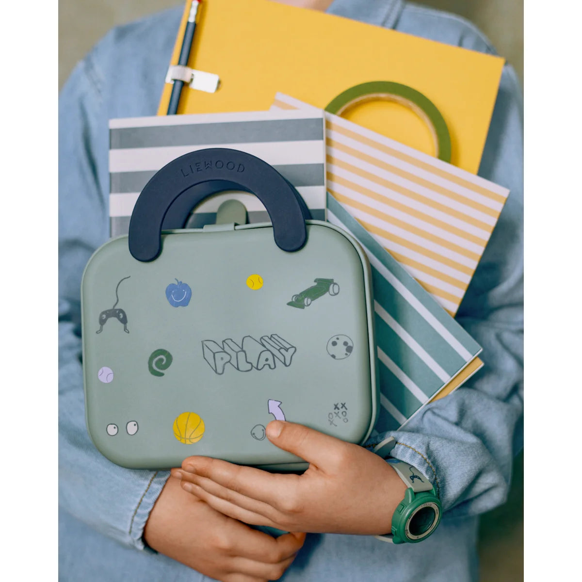 Eine faltbare liewood elara lunchbox in staubigem pfefferminz mit navy blauem griff und spielerischen sportstickern
