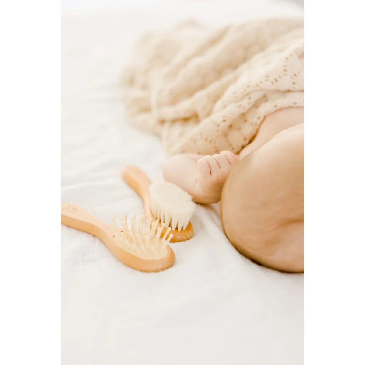Holz-Babypflegeset mit Bürste und Kamm neben schlafendem Baby