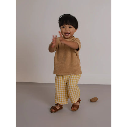 Fröhliches Kleinkind in Fisherman Pants Honeycomb Gingham, Beige Top, Sandalen