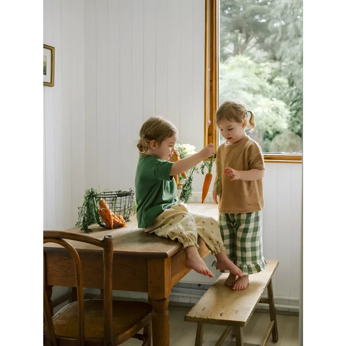 Zwei junge Kinder mit Frill Culottes Dill Gingham spielen mit Karotten