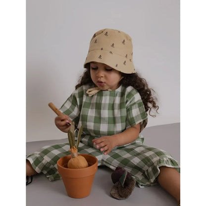 Kind mit beigem Eimerhut, Dill Gingham Frill Culottes auf dem Boden sitzend