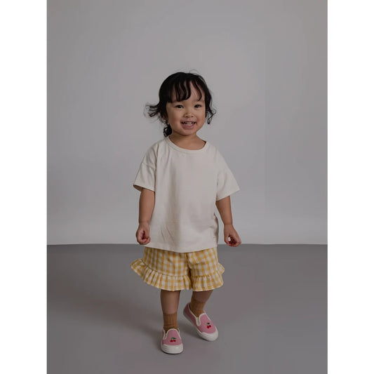 Kind auf dem Rücken in Frill Shorts Honeycomb Gingham