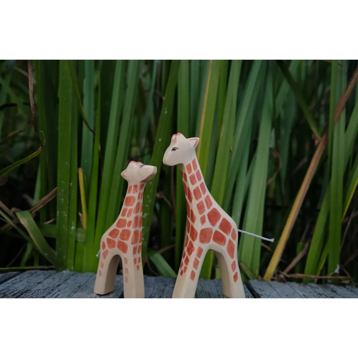 Zwei Holzspielzeug-Giraffen mit hellbraunen Körpern und orange-roten Flecken