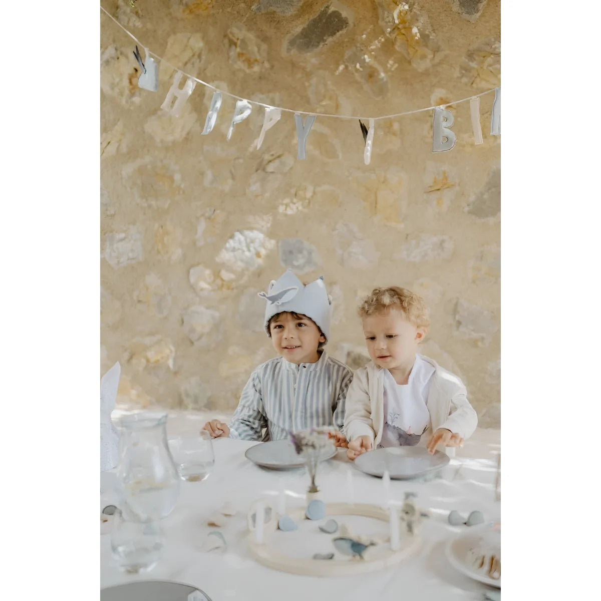 Zwei kinder feiern unter einer blauen girlande happy birthday mit nachhaltigen baby- und kinderprodukten
