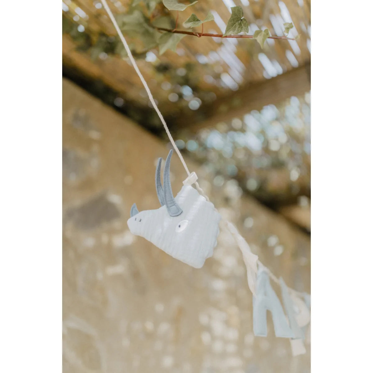 Light blue plastik triceratops girlande mit grauen hörnern und schwarzen augen als ökologische baby- und kinderprodukte