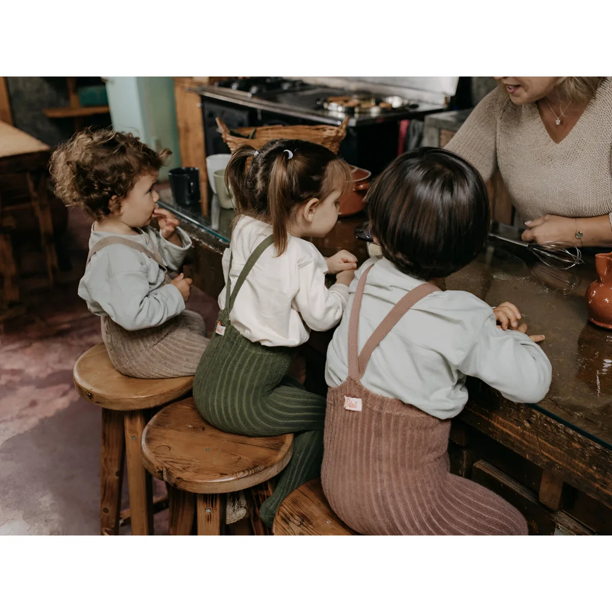 Drei junge Kinder sitzen auf Hockern am Tisch mit Granny Teddy Strumpfhose