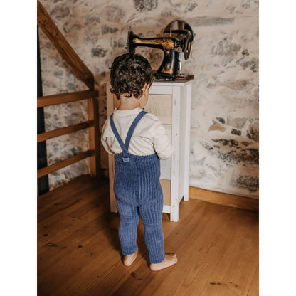 Kind im blauen Overall steht vor einer antiken Nähmaschine für Granny Teddy Strumpfhosen