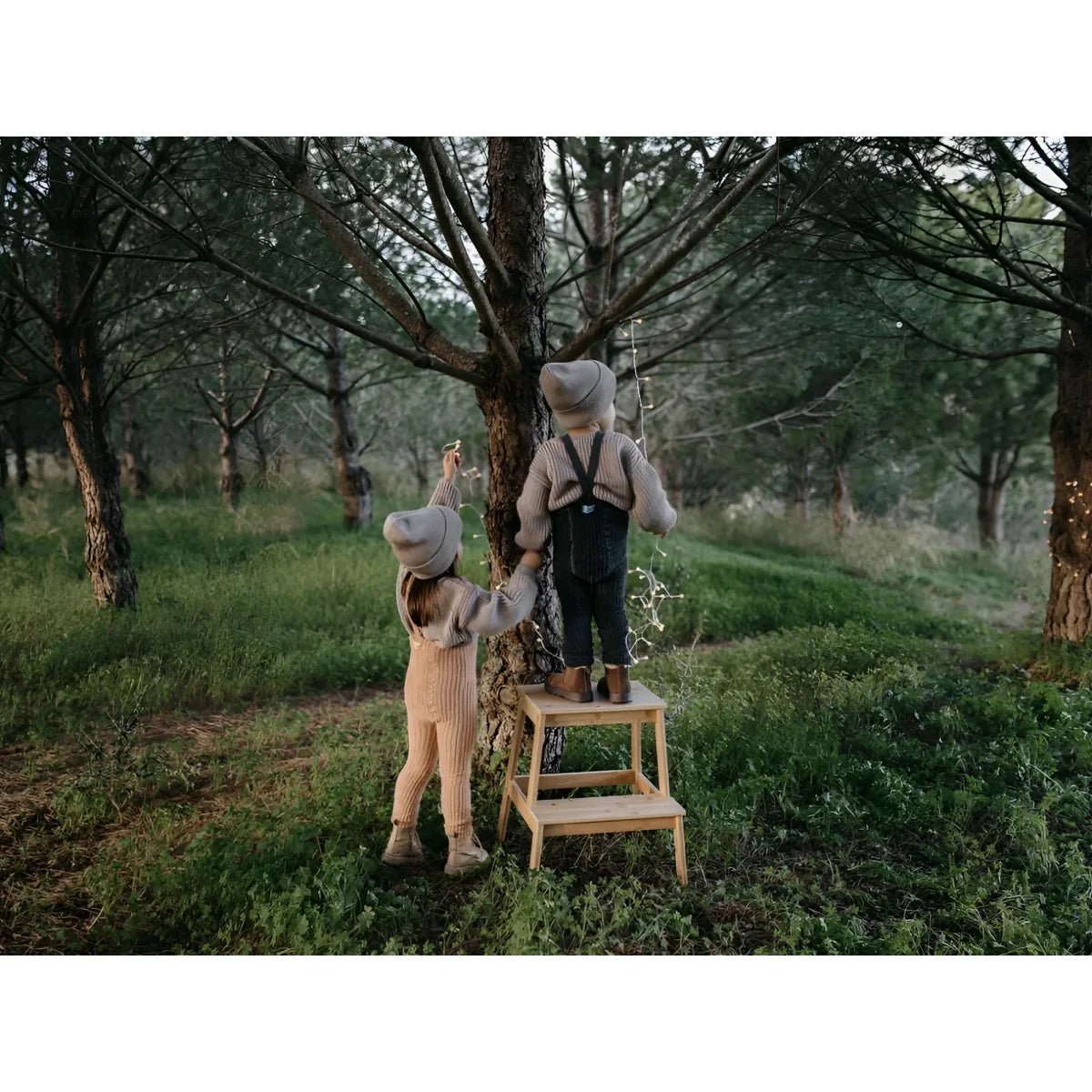 Zwei Kinder auf einer Holztrittleiter im Obstgarten mit Granny Teddy Strumpfhose