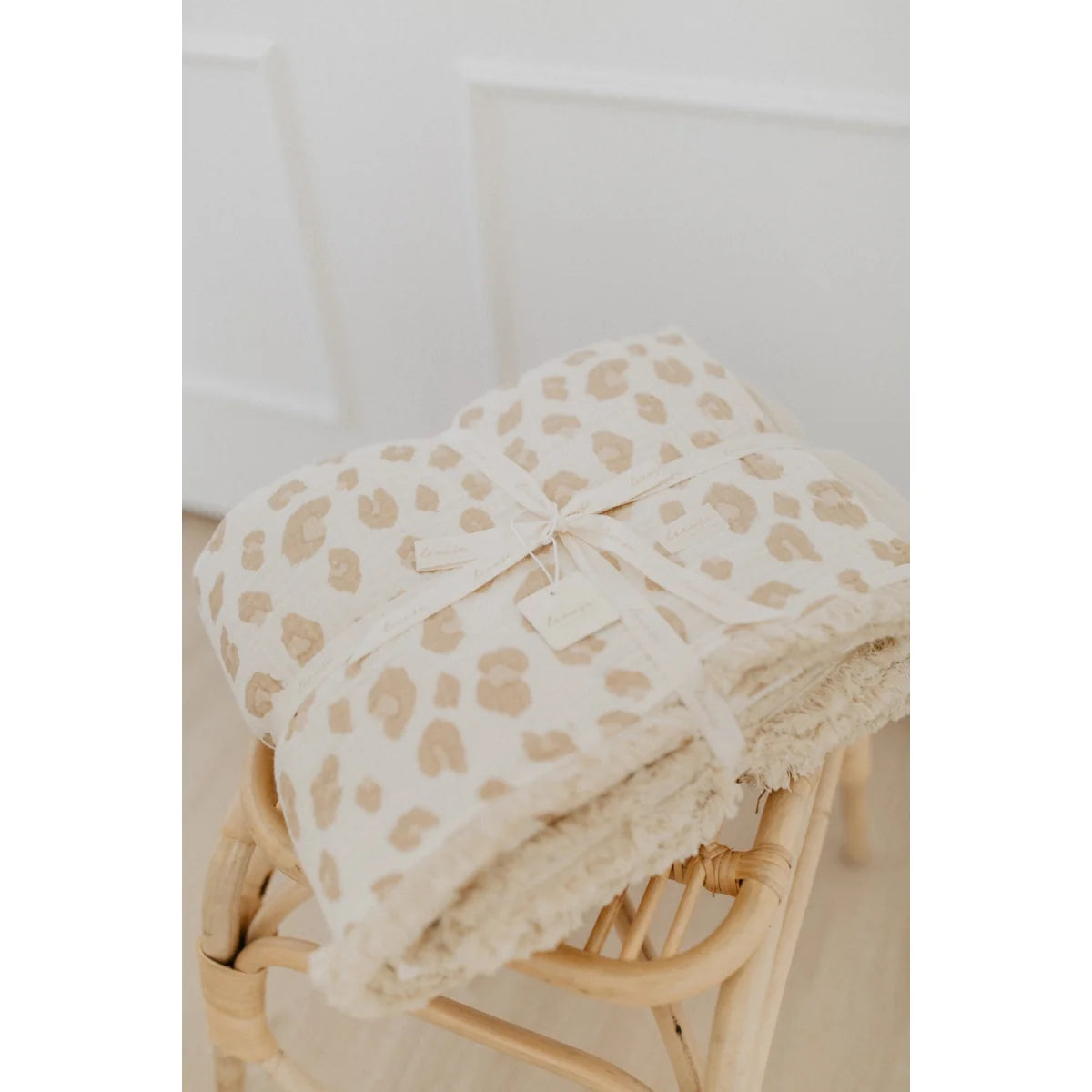 Gefaltete Tagesdecke mit Leoprint und cremefarbenem Band, passend zum Produkt Grosse Tagesdecke zum Wenden leoprint