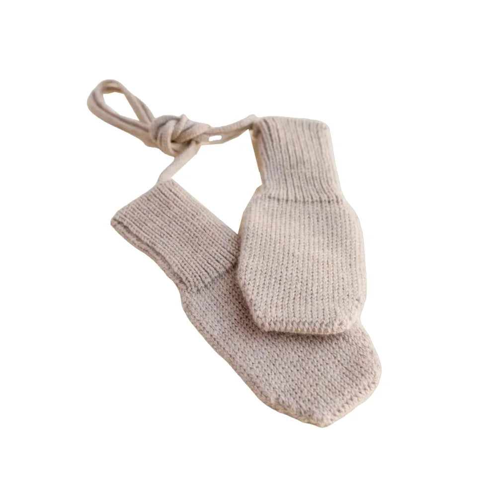 Beige gestrickte Babyhandschuhe mit einer Schnur verbunden, Modell Handschuhe Sand