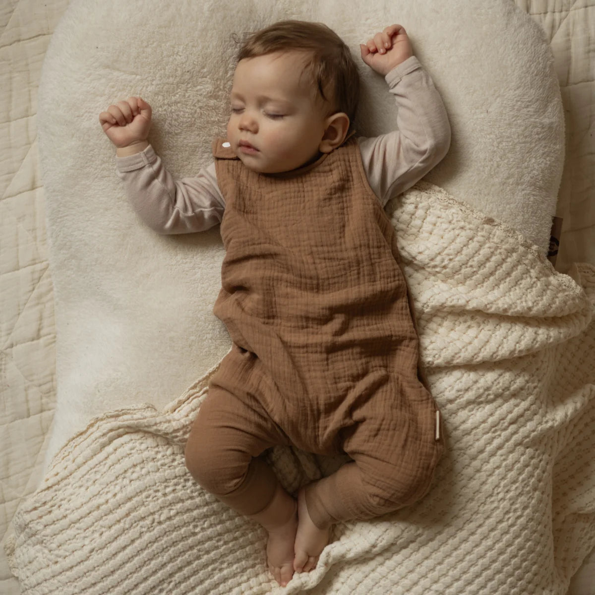 Schlafendes Baby im braunen Overall mit ausgestreckten Armen, Harem Romper beige