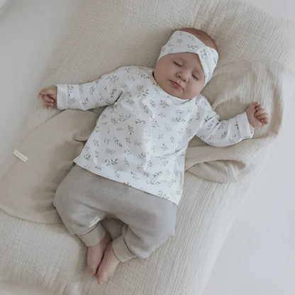 Neugeborenes Baby schläft in einem gestreiften Oberteil mit Haarband ’Blätter’