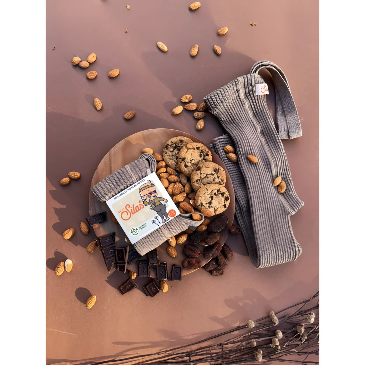 Holzplatte mit Cookies, Schokoladenstücken, Nüssen und einem Paket Blondies