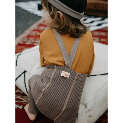 Kind mit grauem Corduroy-Latzkleid und senfgelbem Shirt für Hippy Footless Strumpfhosen