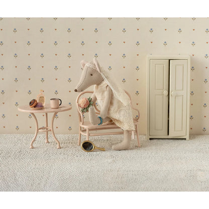 Eine cremefarbene, spitzenbesetzte stofffuchspuppe mit einem zarten schleier sitzt auf einem mini-stuhl