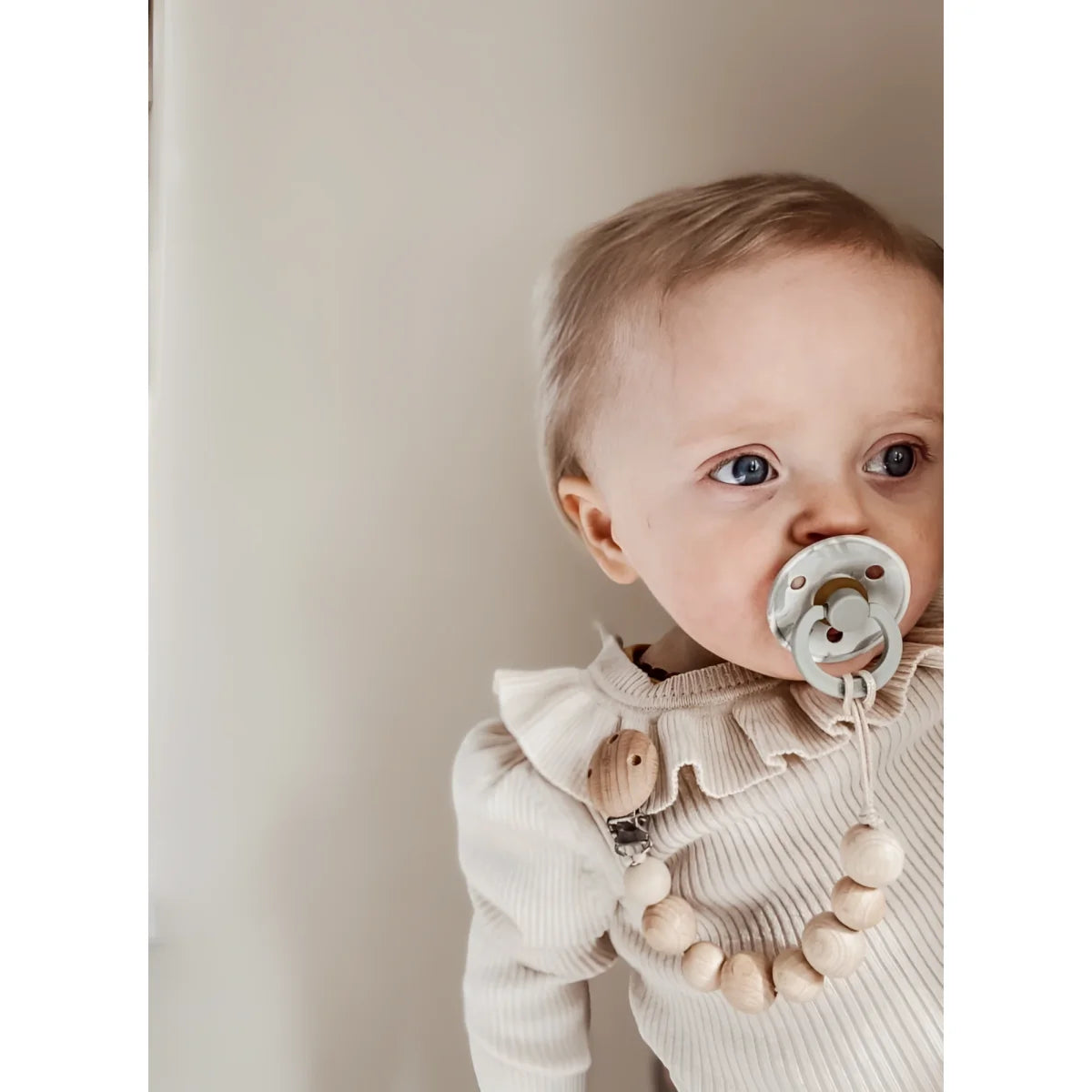 Baby mit großen Augen, Schnuller und Rüschenshirt, Holz Nuggikette in Honigfarbe
