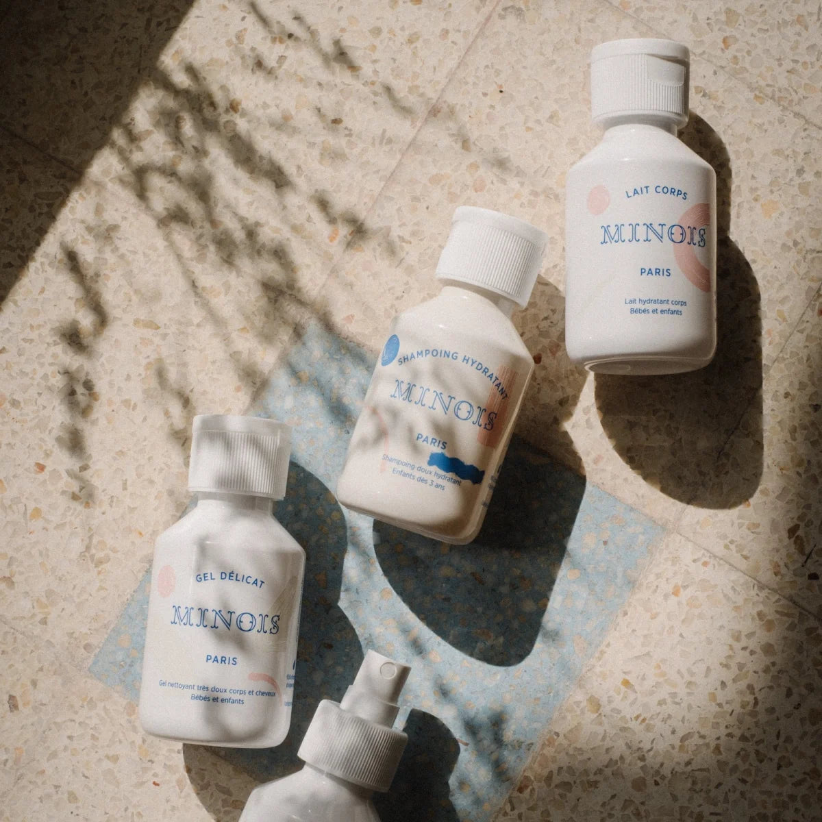 Weiße plastikflaschen mit minimalistischem etikett von minois paris, hydrierendes shampoo 300 ml, gel delicat und lait corps