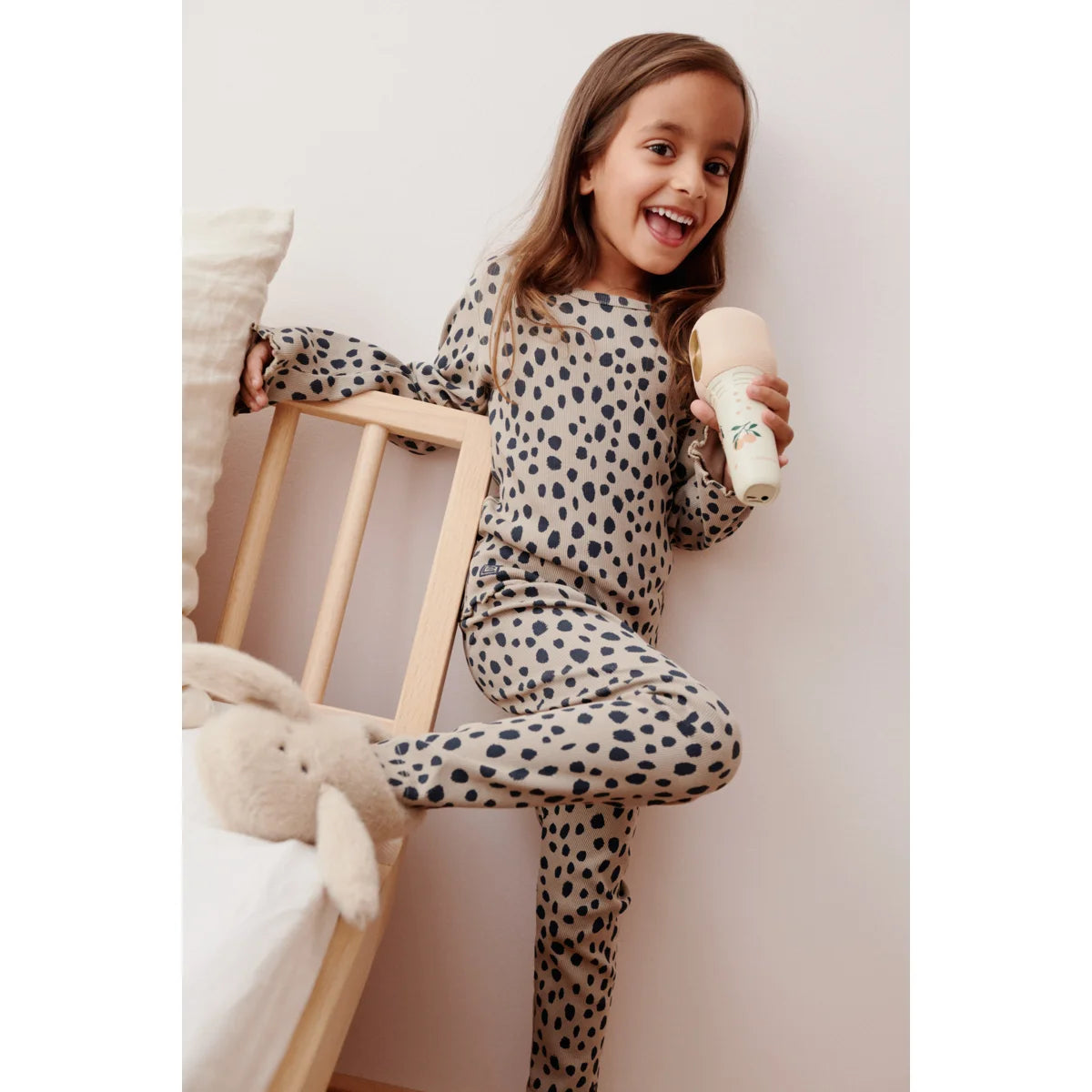 Kind in beigeschwarzem Leopard-Pyjama mit Beinta Mikrofon