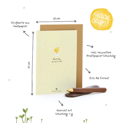A pale yellow seed paper greeting card with a yellow chick illustration and the text hurra du bist da