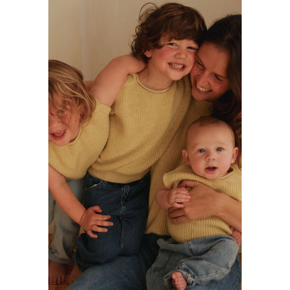Frau und drei Kinder lachen in gelben Tops und blauen Jeans bei Kids Vest Harvey