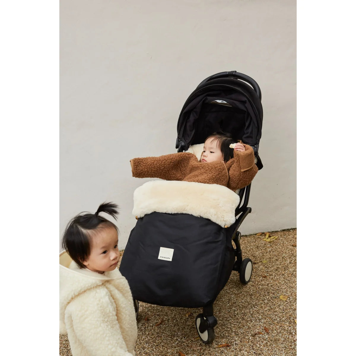 Baby stroller with a black base and brown cushioned seat cover from Kinderwagen Fusssack Puffmuff