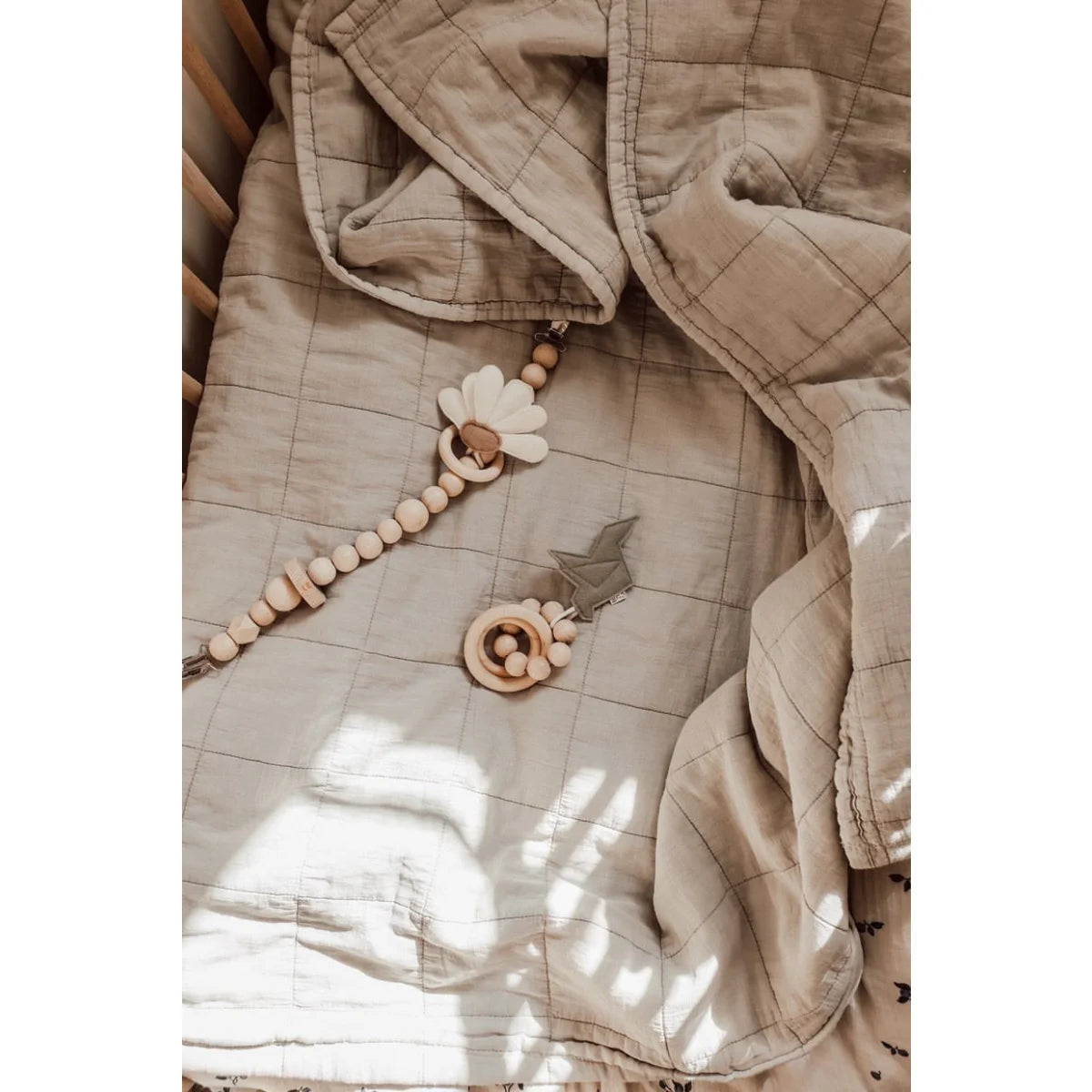 Beige gesteppte Jacke mit Holzperlenaccessoires neben Kinderwagenkette Daisy Daylight