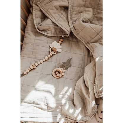 Beige gesteppte Jacke mit Holzperlenaccessoires neben Kinderwagenkette Daisy Daylight