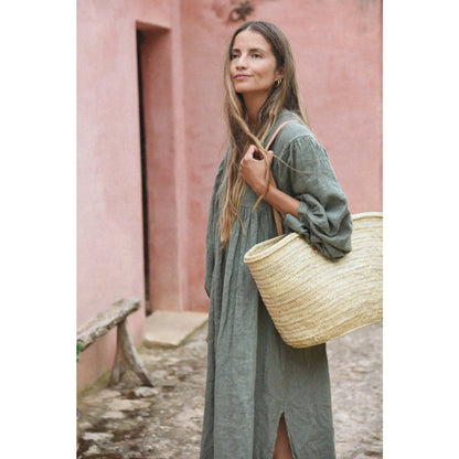 Frau in langem grünen Kleid mit Strohtasche vor Produkt Kleid Bonita | Fern