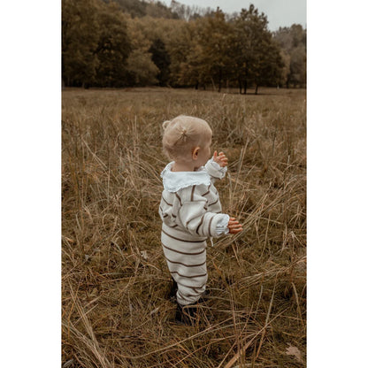 Kleinkind in gestreiftem Outfit steht im hohen Gras, Knit Pants Stripe | Coffee