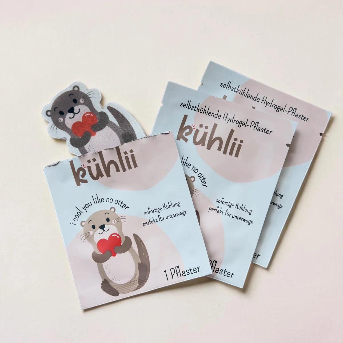 Kühlii selbstkühlende hydrogelpflaster mit grauen und weißen ottermotiven in pastellblauer verpackung mit roten herzen