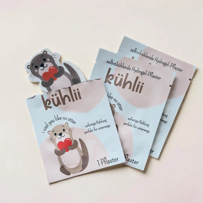 Kühlii selbstkühlende hydrogelpflaster mit grauen und weißen ottermotiven in pastellblauer verpackung mit roten herzen