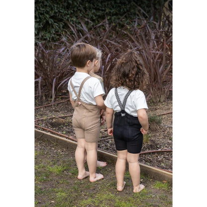 Drei Kinder in Hosenträger-Shorts mit klassisch schwarz-weißem Karomuster