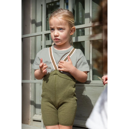 Kind in grünen Strickshorts und grauem Shirt mit Trägern für Kurze Strumpfhose