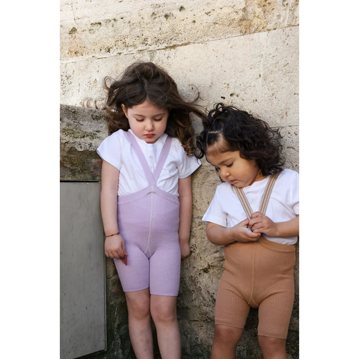 Zwei mädchen tragen kurze strumpfhose mit träger in lavendel und beige aus nachhaltiger babykleidung schweiz