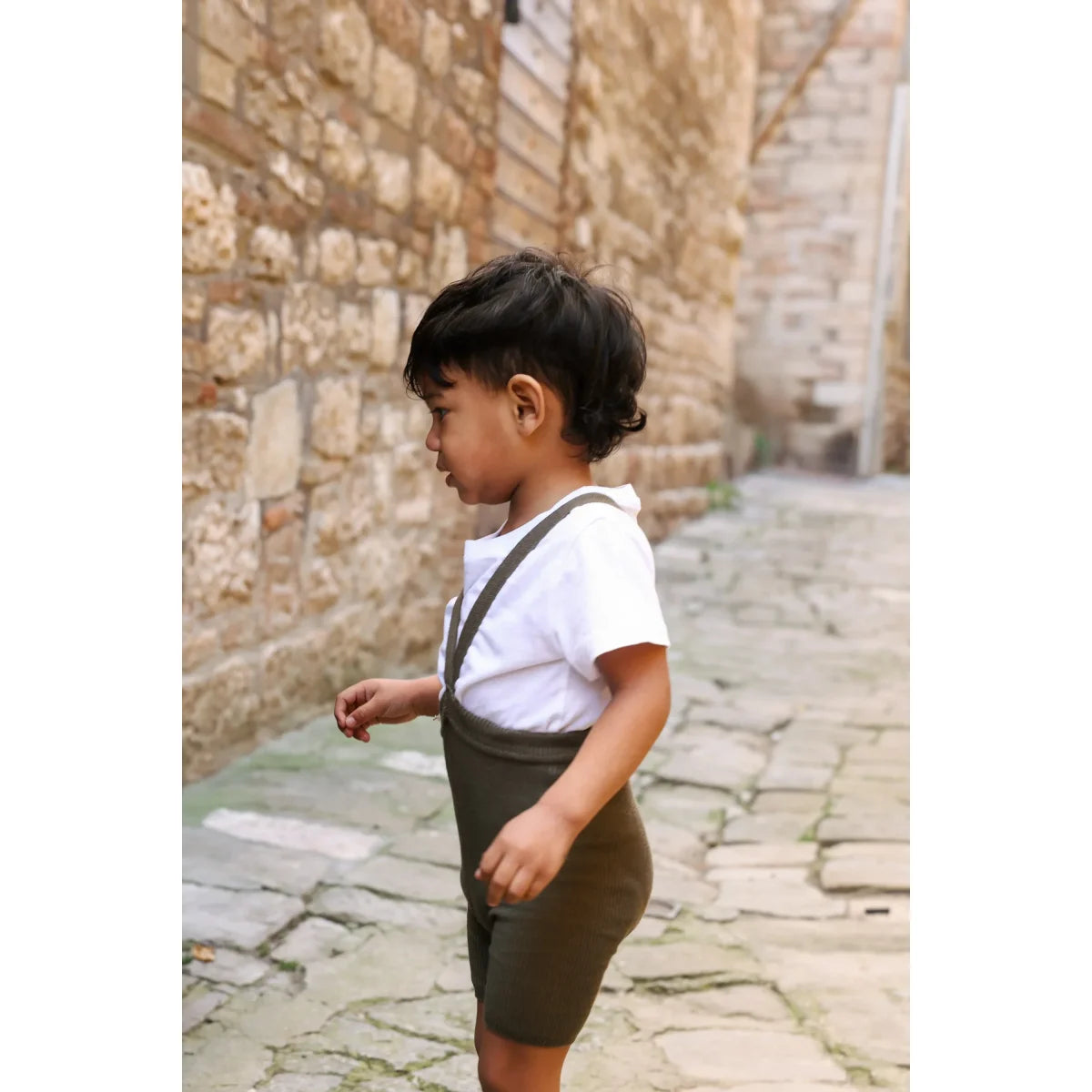 Ein junges kind trägt kurze strumpfhose mit träger seaweed brown in nachhaltige babykleidung schweiz aus ökologischem