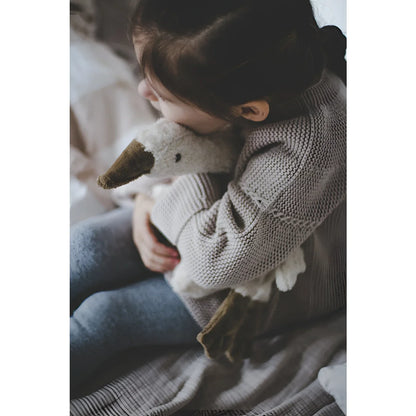 Kind umarmt ein kleines weißes Kuscheltier Gans