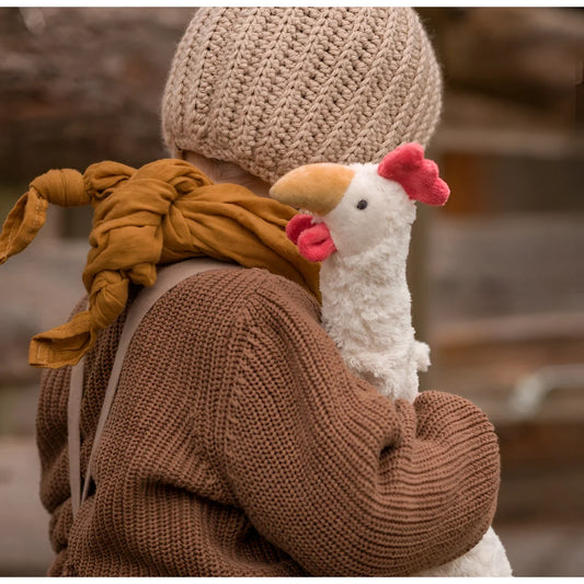 Plüsch weißes Huhn Spielzeug auf der Schulter einer Person im gestrickten Outfit