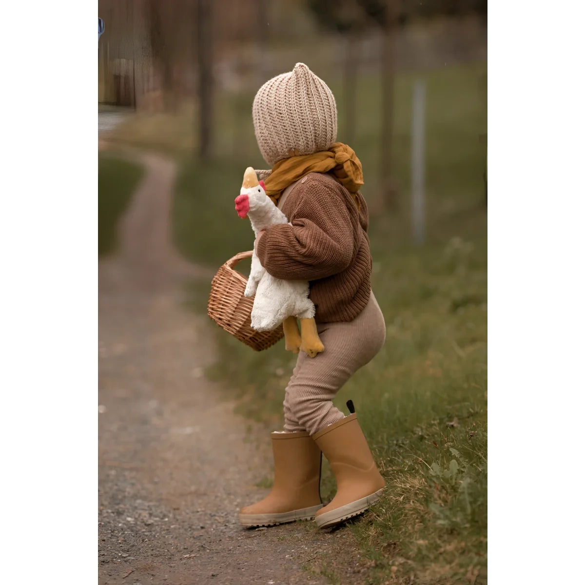 Kind in warmer Herbstkleidung mit einem Kuscheltier Huhn klein in Weiß