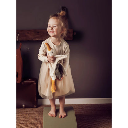Junges Kind im cremefarbenen Kleid mit Kuscheltier Möwe klein in der Hand