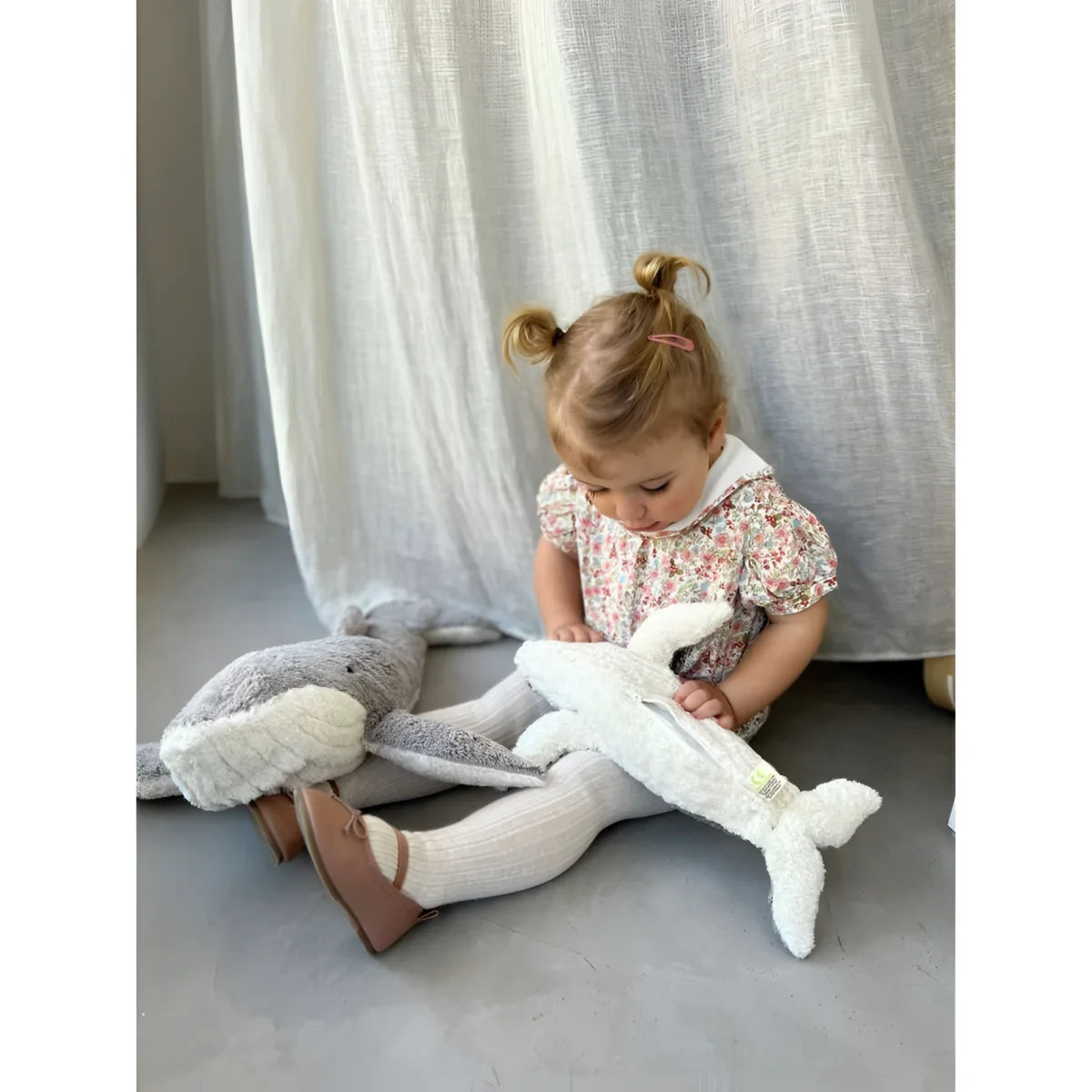 Junger Kind spielt auf dem Boden mit Kuscheltier Wal klein