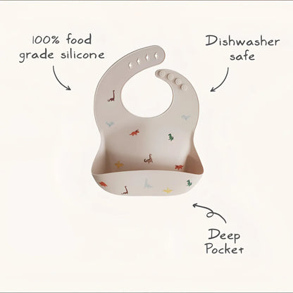 Beige silikonlätzchen mit bunten dinosauriermotiven und tiefer tasche für nachhaltige babykleidung schweiz