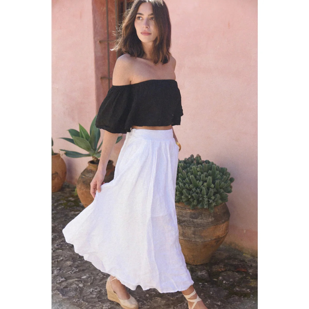 Frau in schwarzem Off-Shoulder-Top und weißem Rock vor Produkt Leinen Rock Alba Blanco