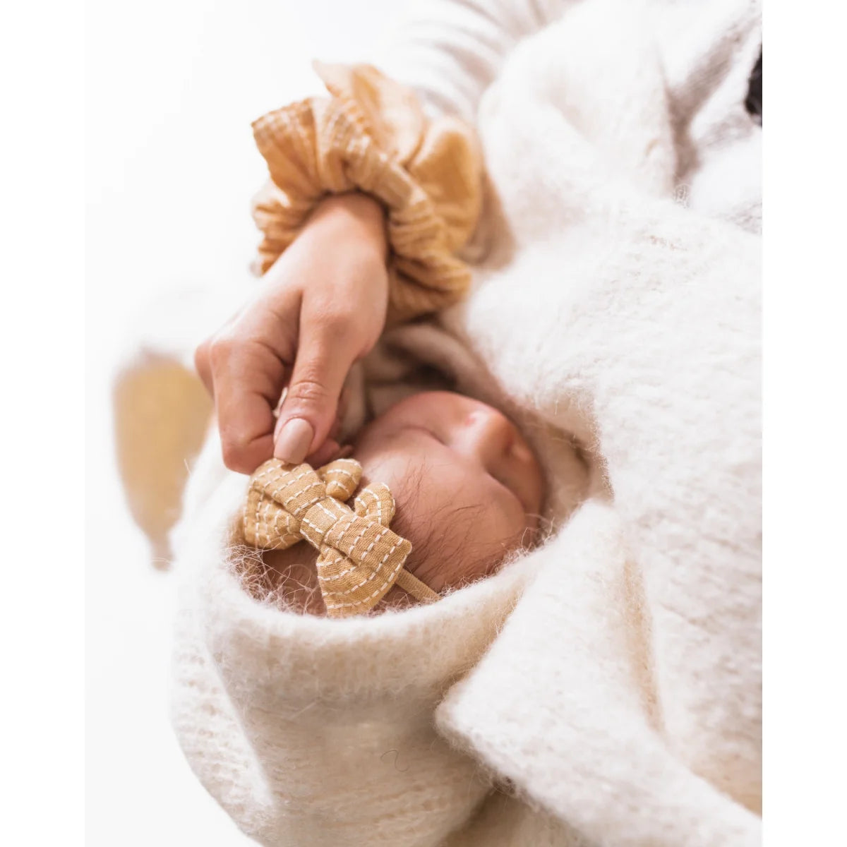 Hand hält ein kleines Stofftier neben dem Little Bow Headband von Little Daisies
