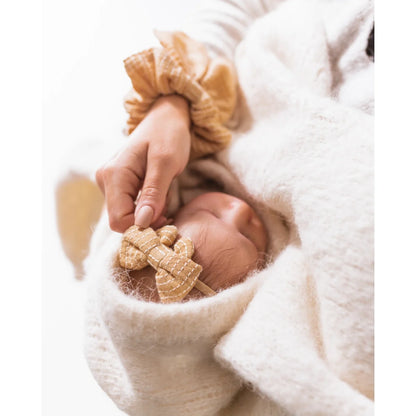 Hand hält ein kleines Stofftier neben dem Little Bow Headband von Little Daisies