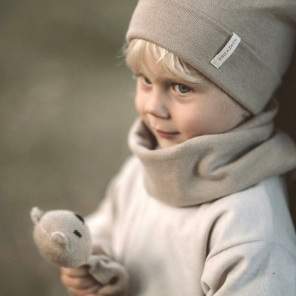 Junge mit beigem Hut und Schal, hält ein kleines Stofftier, trägt Lounge Sweater