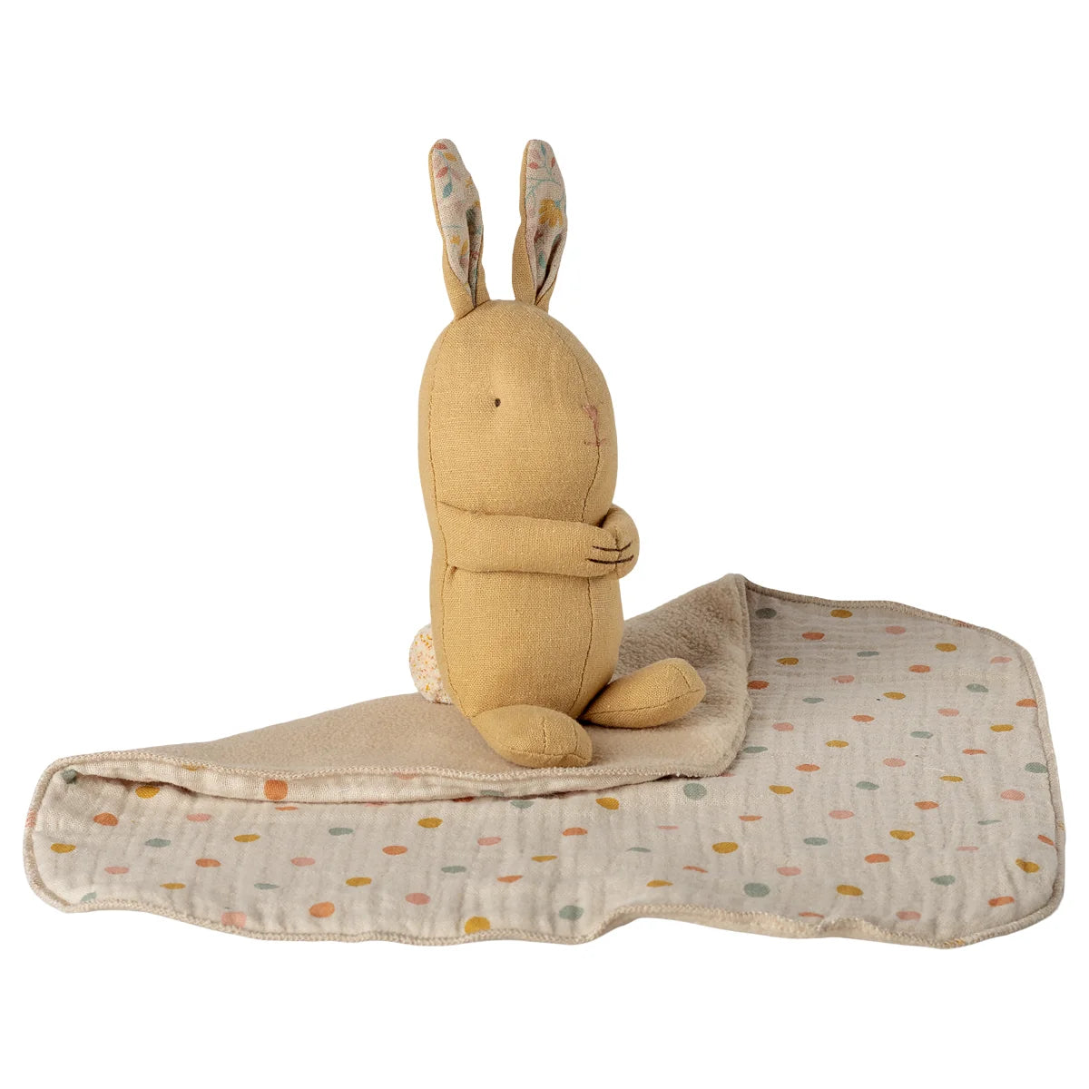 Ein weicher beiger plüschhase mit bestickten details auf einer gepunkteten decke lullaby friends has mini cremegelb