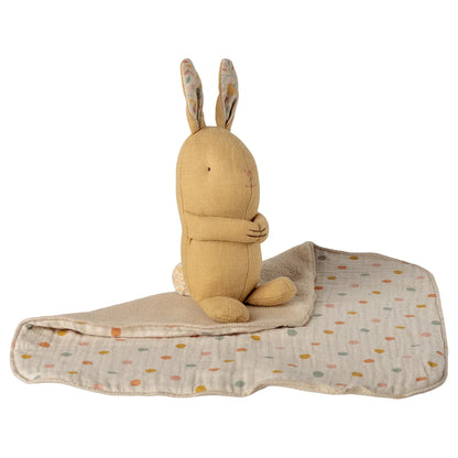 Ein weicher beiger plüschhase mit bestickten details auf einer gepunkteten decke lullaby friends has mini cremegelb