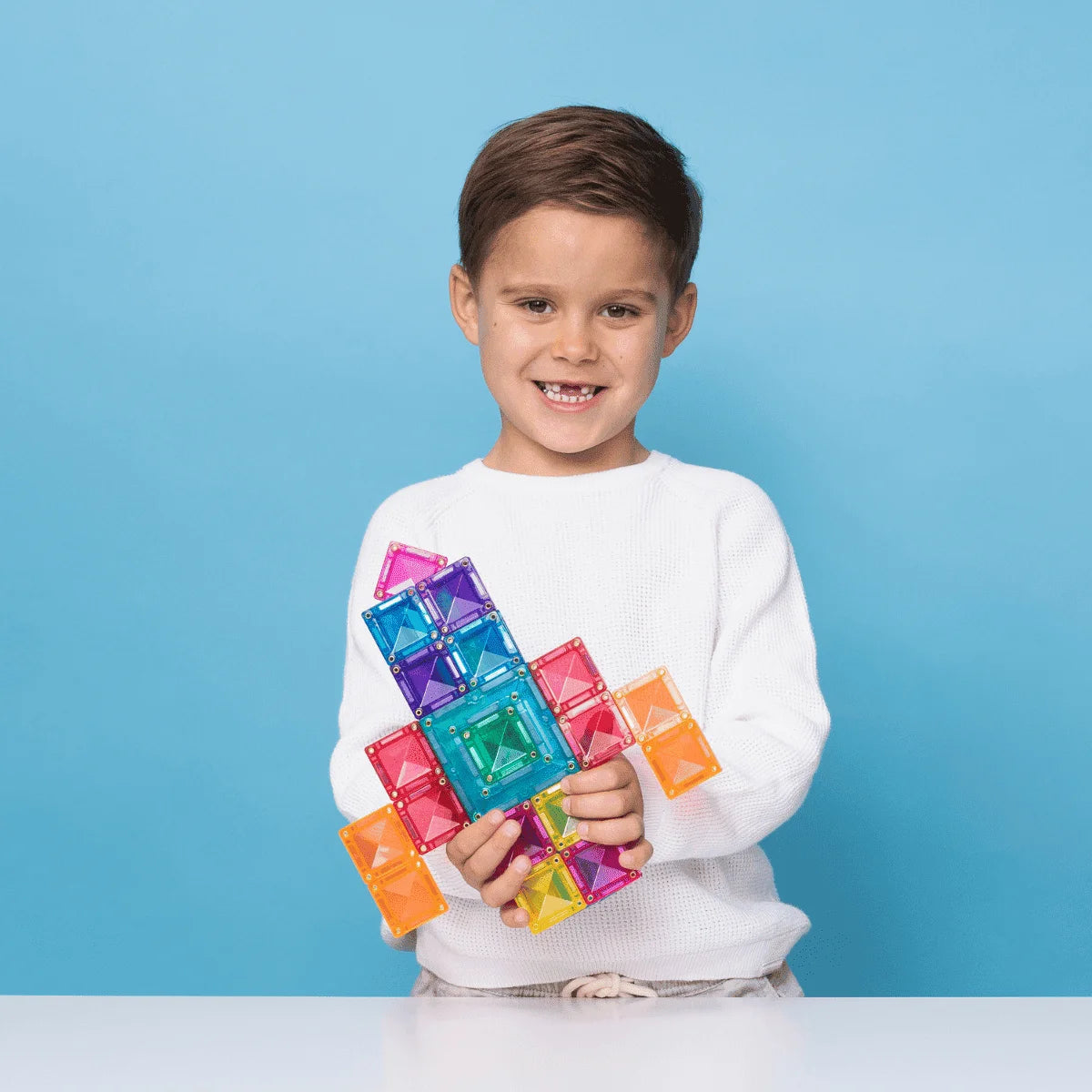Ein junger Junge hält stolz eine bunte Magnetbaustein-Rakete aus dem Bright Portal Pack