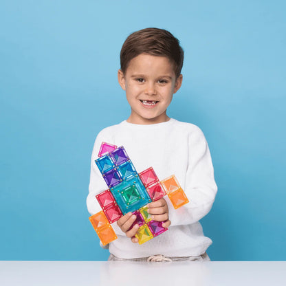 Ein junger Junge hält stolz eine bunte Magnetbaustein-Rakete aus dem Bright Portal Pack